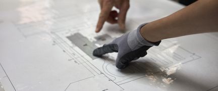En byggritning. Två personer pekar på detaljer på ritningen.