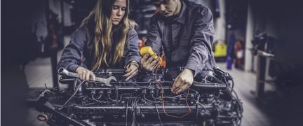 Två personer som mekar med en motor.