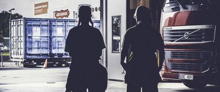 Två personer står i transporthallen.