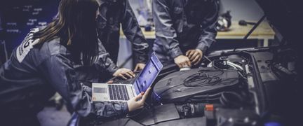 Elever felsöker en motor med hjälp av en dator.