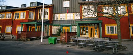 Huvudentrén till Nya Varvetskolan. Skolgården med några bänkar, en flaggstång och ett träd syns i bakgrunden.