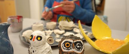 En person målar keramikkonstverk.