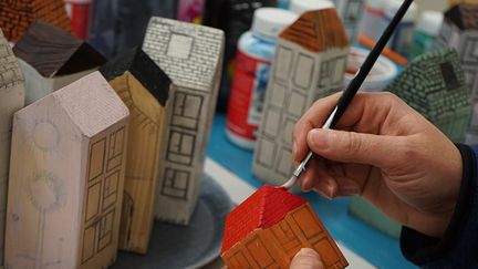 En person målar små trähus.