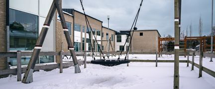 En gunga utanför Kärraskolan med några skolbyggnader i bakgrunden.