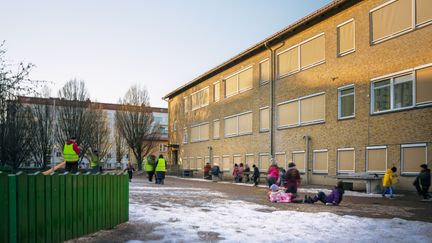 En en grupp barn som leker framför en skolbyggnad.