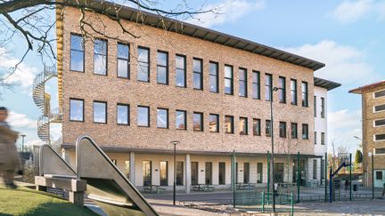 En skolbyggnad med en rutschkana framför sig.