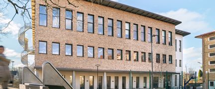 En skolbyggnad med en rutschkana framför sig.