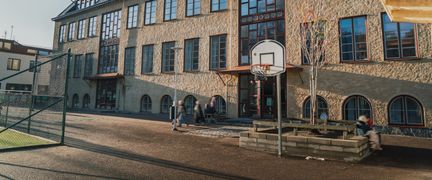 Dalaskolans skolgård men en basketkorg och några personer i bakgrunden.