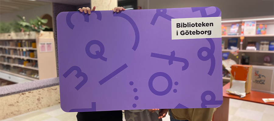 Barn håller upp ett stort bibliotekskort.