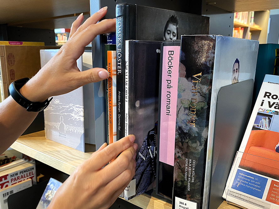 Händer som plockar en bok ur en bokhylla.