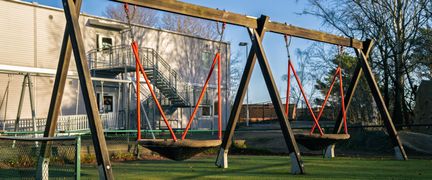 En gungställning på en skolgård med en byggnad i bakgrunden.