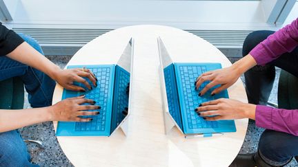 Två datorer mittemot varandra med två personers händer som skriver på respektive dator.