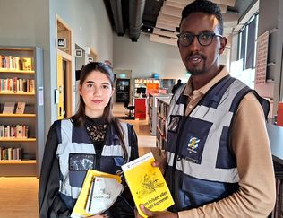 Två invånarguider håller upp broschyren Om kriget och krisen kommer