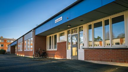 En skolbyggnad med entré med en cykel parkerad utanför.