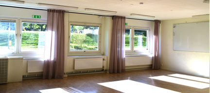 Ett stort rum med ljusinsläpp från fönster. Det finns en whiteboardtavla på väggen.