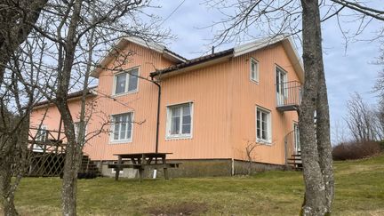 Ett gult trähus med två våningar. Framför huset finns ett fikabord och träd.