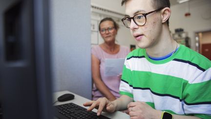 En elev sitter vid sin dator med läraren bredvid. 