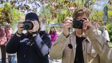Två elever riktar varsin kamera riktade mot oss. 