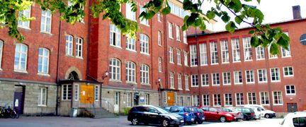 Styrmansgatan med ingång från gården, bilar står parkerade utanför och det är några trappsteg upp till entrén. 