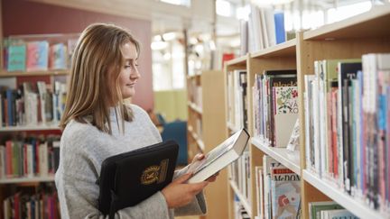Foto av en elev som läser en bok i skolbiblioteket. Foto av Frank & Earnest