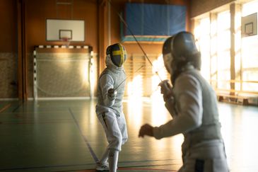 Foto på två elever som fäktas i skolans idrottshall. Foto av Valentin Experience