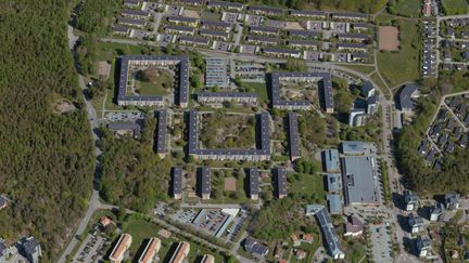 En drönarvy över Norumshöjd. Ett skogsområde ligger till vänster. Till höger bostadslängor.