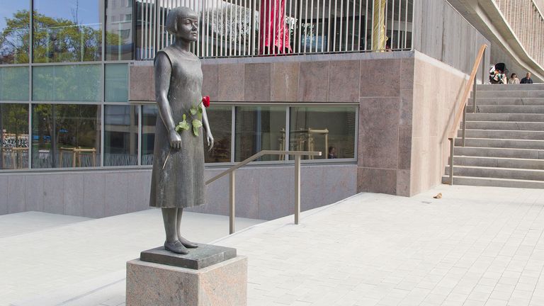 Staty av Karin Boye framför Stadsbiblioteket. Karin har en röd ros i handen.