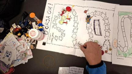 Foto ovanifrån av ett brädspel och en hand som håller i en spelpjäs