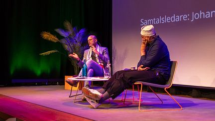 Två personer sitter på en scen och samtalar.