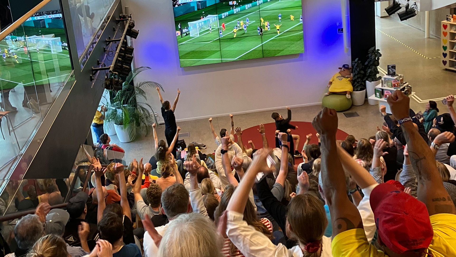 Publik som tittar på en fotbollsmatch och höjer armarna i luften