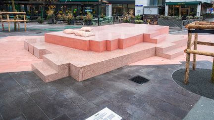 Ett rosa konstverk som tar plats i tre lager staplade på varandra i olika material. Överst ligger tre rosa kuddar i marmor.