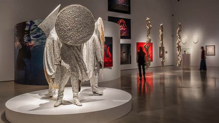 Installationsbild med en skulptur i förgrunden och fotografi i bakgrunden