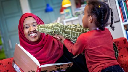 Mamma läser med sitt barn på biblioteket