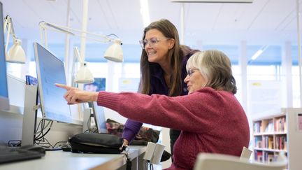 Två personer tittar på en datorskärm som den ena personen pekar på.