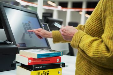 Besökare lånar böcker vid självservicedisken