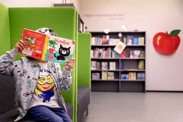 Barn läser bok vid äppelhyllan