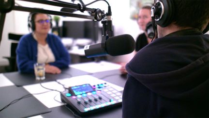 Tre personer i en poddstudio med mikrofoner och hörlurar
