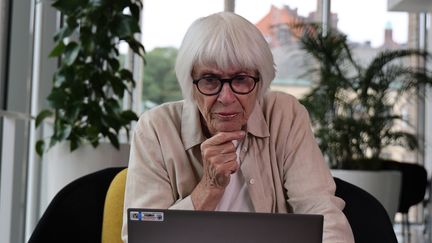 En äldre kvinna tittar fundersamt på en datorskärm