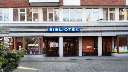 Foto av en fasad och en blå skylt med texten 