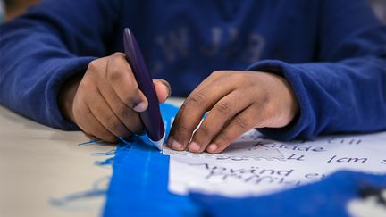  Ett foto av händer som markerar ett blått tygstycke med vit krita.