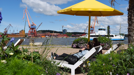Två personer ligger i solstolar och tittar ut över Göta älv.
