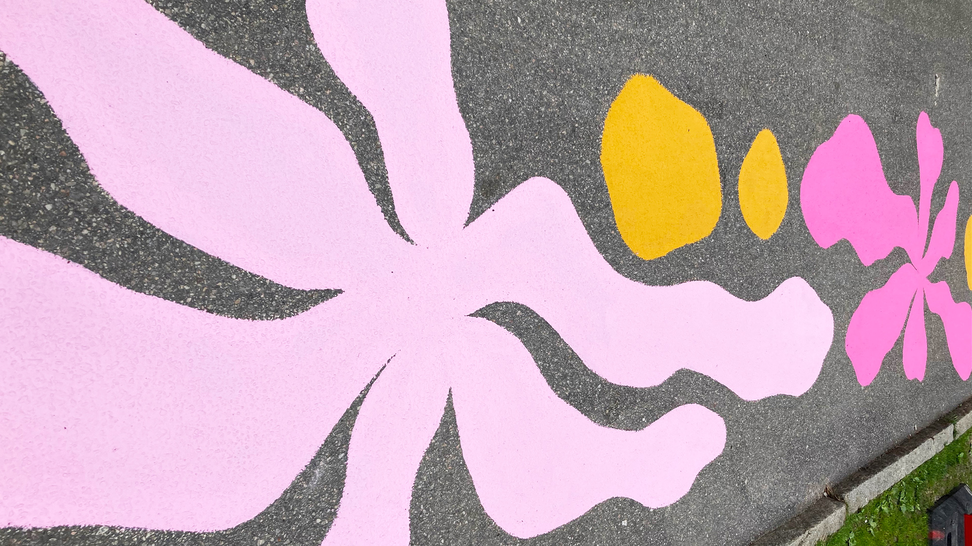 Bild på målningar på asfalten på Gröna Gatan. Färgglada blommor i rosa och gula nyanser syns på denna bild.