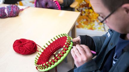 En person gör ett hantverk med garn. 