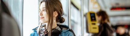 Person på buss tittar ut genom fönstret och ler