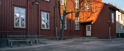 En ingång till Hagaskolan med några bänkar och ett träd i bakgrunden.