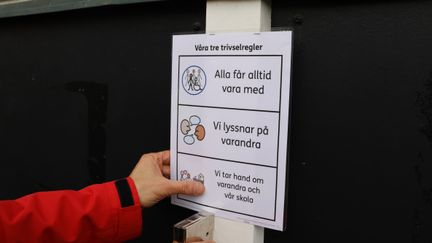 En person som håller en lapp som beskriver 3 trivselregler.