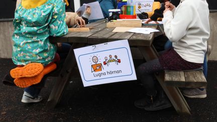 Några barn som pysslar på ett utomhusbord.
