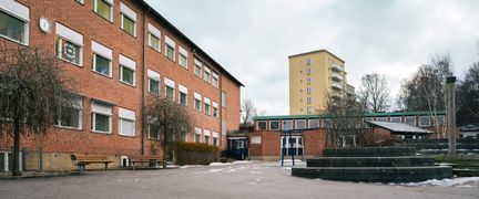 Guldhedsskolans skolgård med huvudbyggnaden och några bänkar i bakgrunden.