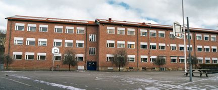 Guldhedsskolans skolgård med några basketkorgar och bänkar i bakgrunden.