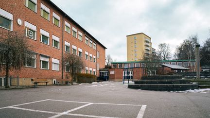 Guldhedsskolans skolgård med huvudbyggnaden och några bänkar i bakgrunden.